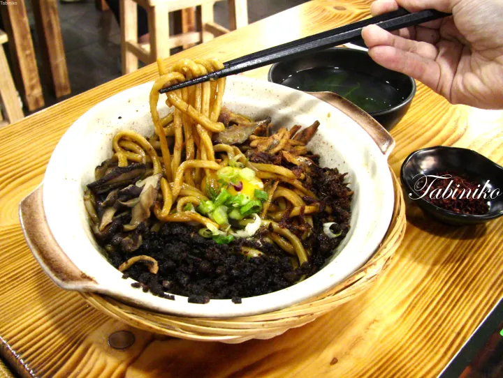具材を乗せた太麺を箸で持ち上げる陶器のボウル。
