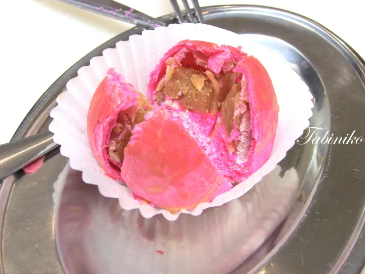 金属製の皿の上で、白い紙カップに入ったピンク色のサクサクした焼き菓子が切られている。