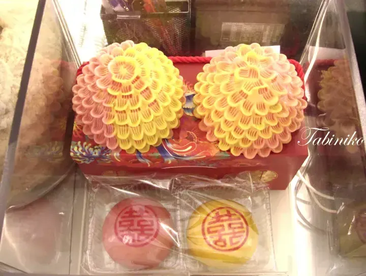 Traditional Chinese wedding pastries including intricate flower-shaped cakes and round buns stamped with the double happiness symbol.