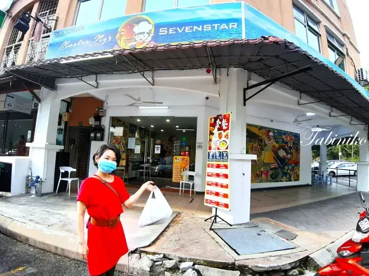 A woman in a red dress holding a takeout bag stands outside Restoran Master Ng&rsquo;s Sevenstar.