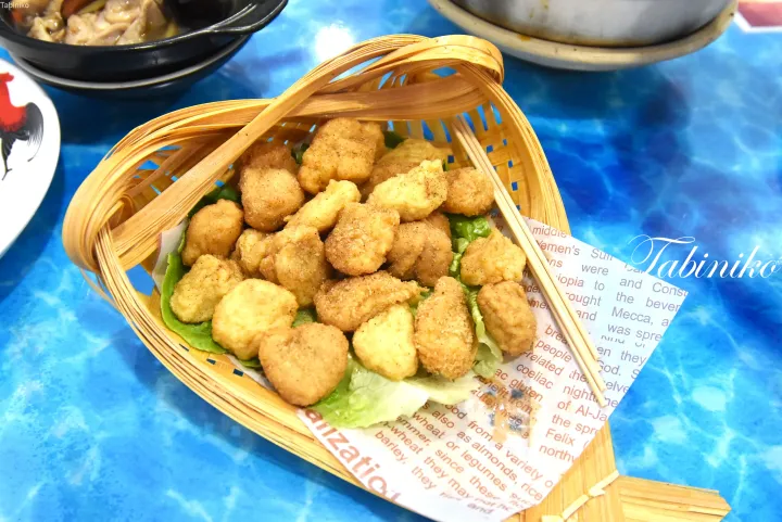 青いテーブルの上の竹籠に盛られた黄金色のチキンナゲット。