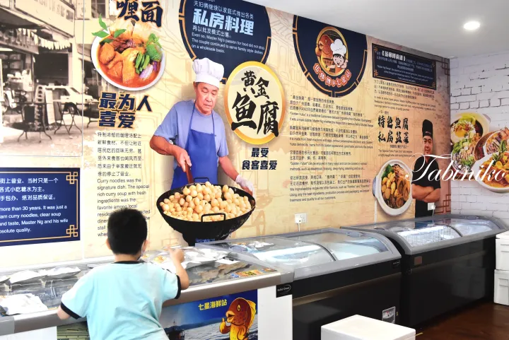 マスター・ンが黄金魚腐やカレー麺を調理する巨大な壁画が飾られた店内で、冷凍ショーケースを覗き込む少年。