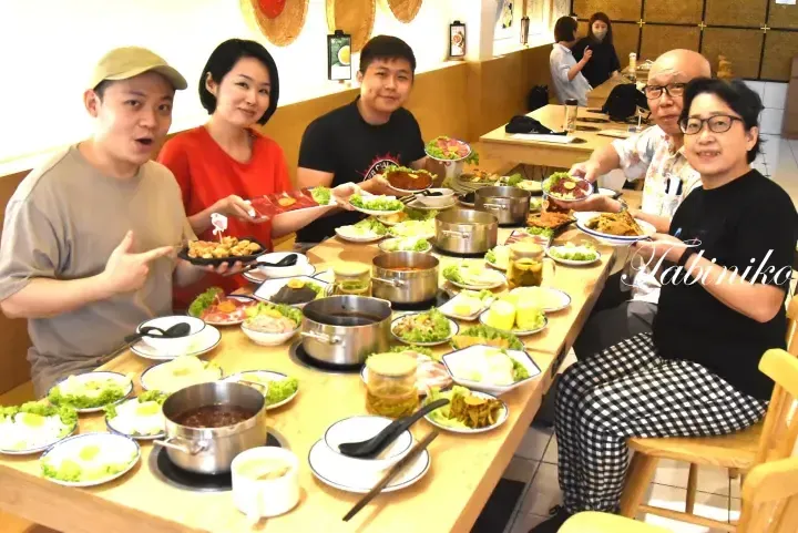 A group of people enjoying a hot pot meal at a restaurant with various dishes and ingredients on the table.