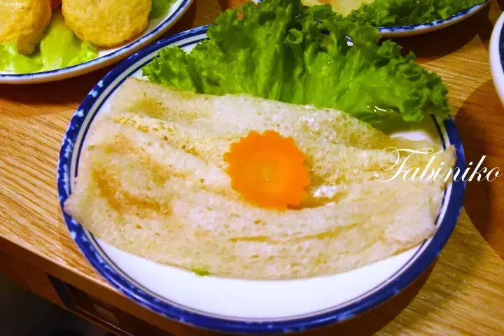 Crispy prawn crackers with a carrot garnish and lettuce on a blue-rimmed plate, served at a Malaysian restaurant.