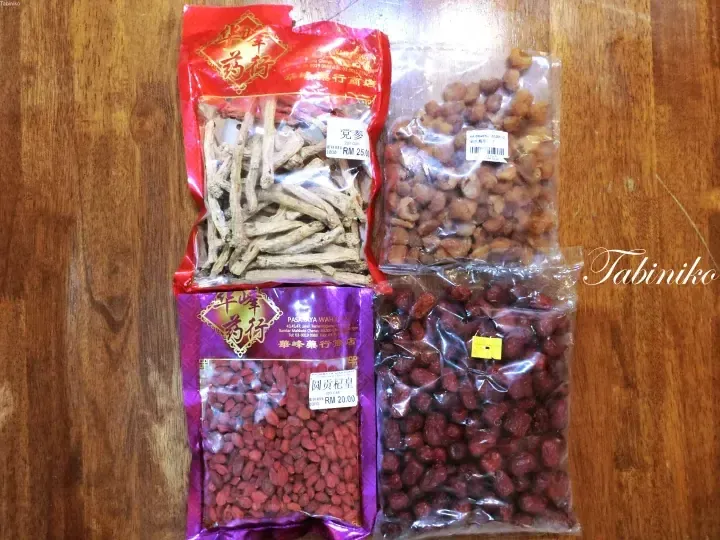 Four bags of traditional Chinese herbs including ginseng, dried longan, goji berries, and red dates on a wooden table.