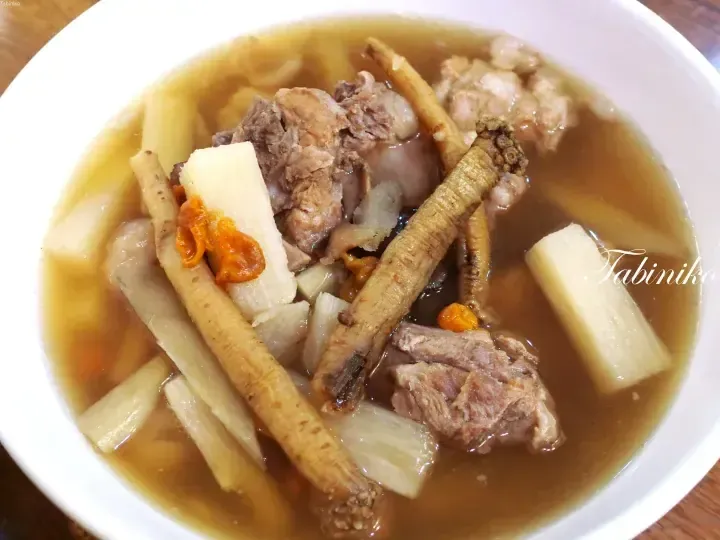 A bowl of herbal pork rib soup with Chinese yam and ginseng roots in a clear broth.