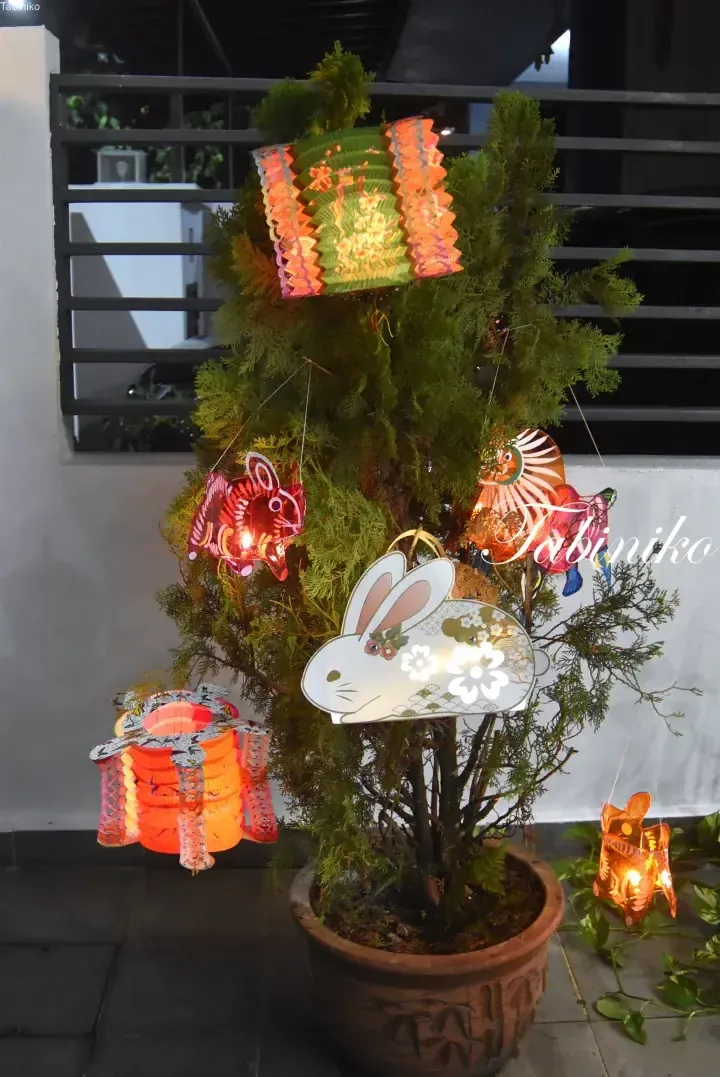 Colorful paper lanterns and rabbit decorations hanging from a potted tree, creating a festive atmosphere.