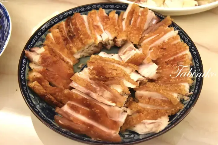 Crispy roasted pork belly sliced and arranged on a blue and white patterned plate.