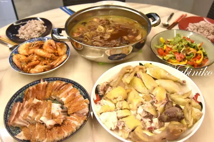 A festive Malaysian feast featuring roasted pork, steamed chicken, stir-fried shrimp, vegetable stir-fry, and a savory stew.