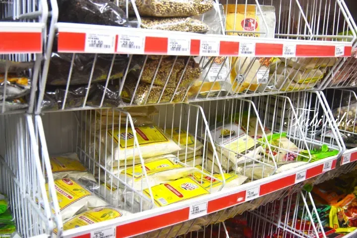 Shelves stocked with packaged spices and seasonings in a Malaysian grocery store, featuring price tags and yellow packaging.