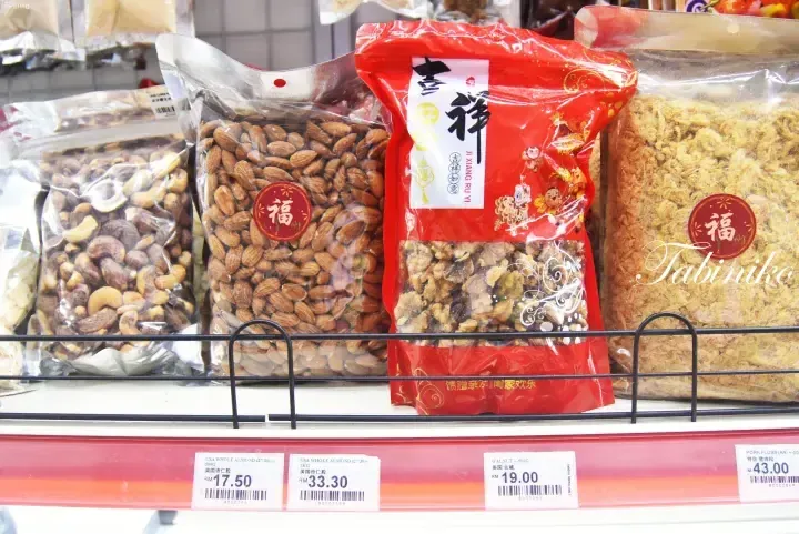 Shelves displaying packaged nuts and pork floss with price tags in Malaysian Ringgit at a Malaysian grocery store.