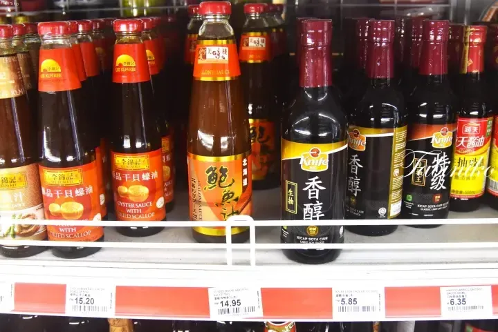Shelves stocked with Lee Kum Kee oyster sauce, Yummy House abalone sauce, and Knife light soy sauce with price tags in Malaysian Ringgit.