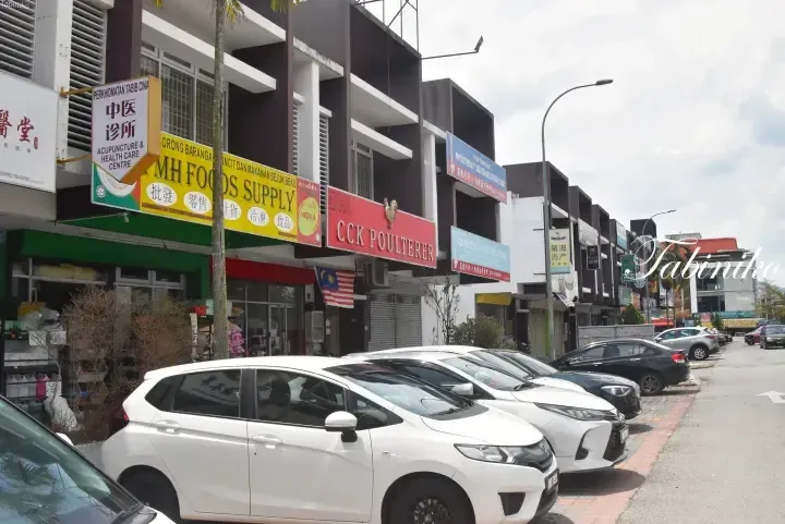 Street view of shop lots in Malaysia featuring MH Foods Supply and CCK Poulterer, with parked cars in front.