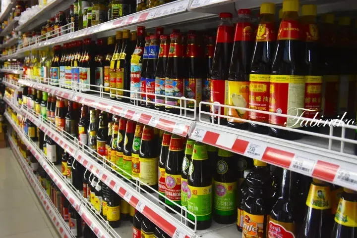 Rows of Lee Kum Kee and Ting Ting sauces neatly displayed on supermarket shelves with red and white price tags.