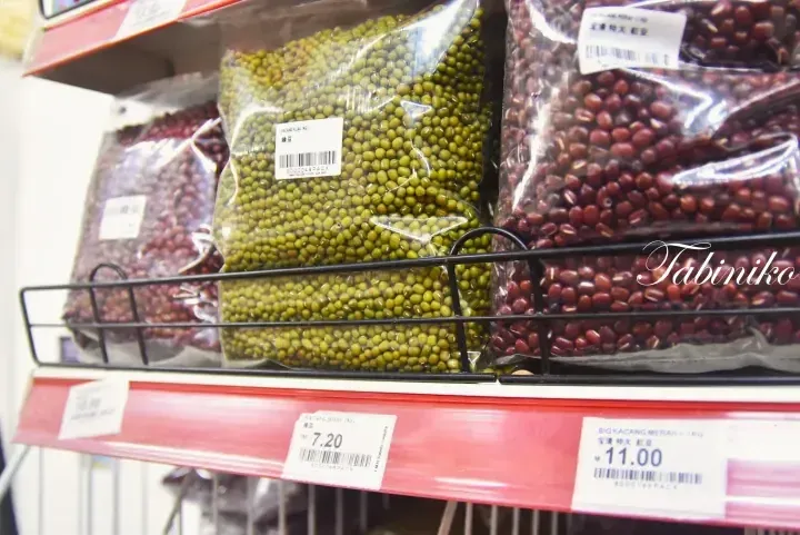 Shelves stocked with bags of green mung beans and red kidney beans priced at RM 7.20 and RM 11.00 respectively.