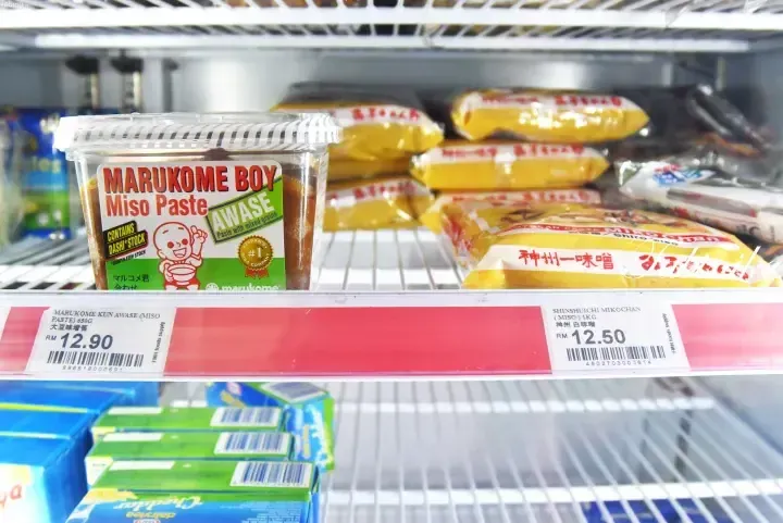 Marukome Boy Miso Paste and Shinshuichi Miko Chan Miso on a supermarket shelf with price tags.