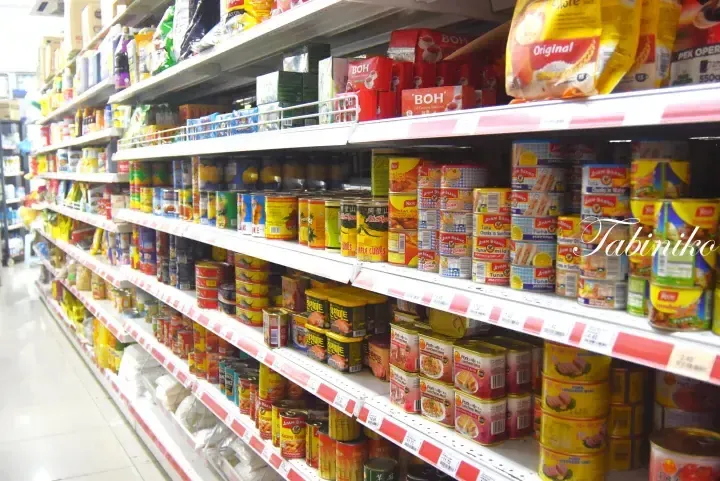 Aisles of canned goods and packaged food products neatly arranged on supermarket shelves in Malaysia