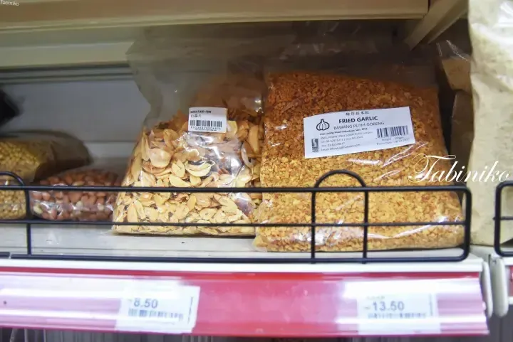 Bags of garlic flakes and fried garlic on a supermarket shelf with price tags showing RM 8.50 and RM 13.50
