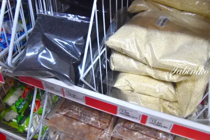 Shelves stocked with bags of black and white sesame seeds at a Malaysian grocery store, showing price tags.