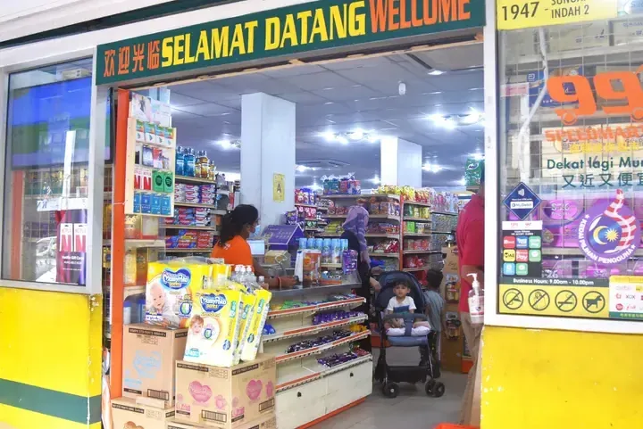 Entrance of 99 Speedmart convenience store with &lsquo;Selamat Datang&rsquo; sign, stocked shelves, and customers shopping inside.