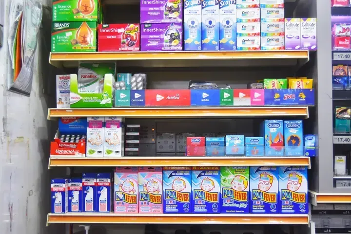Shelves stocked with Malaysian health products like Panadol, Durex, and Kool Fever cooling patches in a pharmacy.