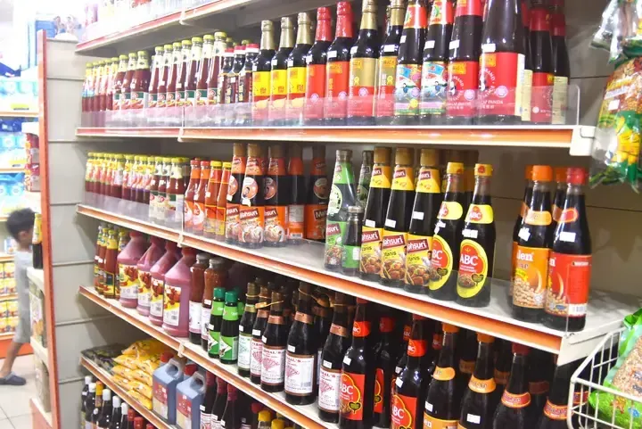 Shelves stocked with various soy sauce brands like ABC and Kicap Panda in a Malaysian grocery store aisle.