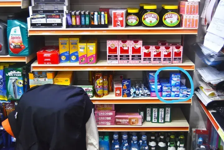 Shelves stocked with Marmite, Vicks VapoRub, and Petronas Sprinta oil at a Malaysian convenience store.