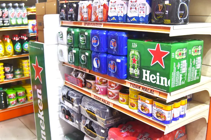 マレーシアのコンビニエンスストアの棚に並ぶハイネケンやタイガービール、缶詰などの商品。