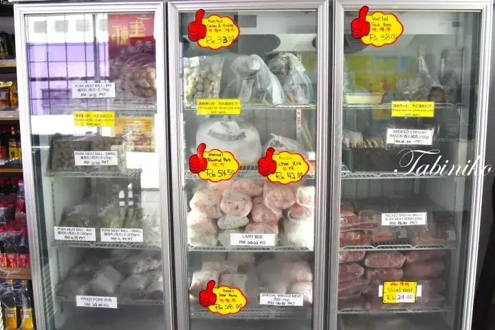 Refrigerated display cases stocked with various frozen pork products like meatballs, roasted pork, and lard with price labels.