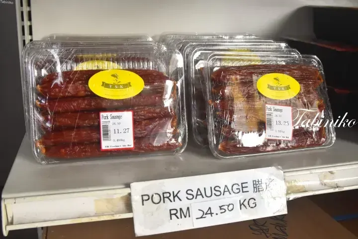 Plastic containers of YSK Freshmart pork sausage displayed on a supermarket shelf with price labels showing RM 24.50 per kg.