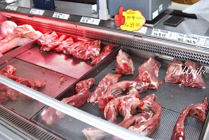 Fresh pork ribs and cuts displayed in a refrigerated meat counter with price labels at a Malaysian market.