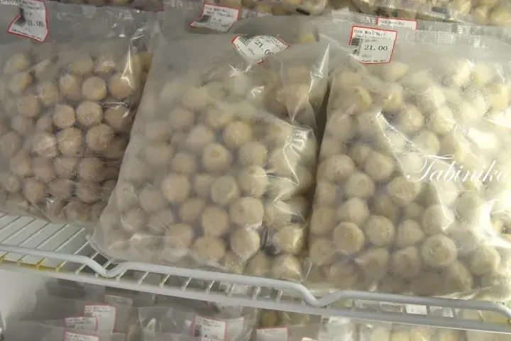 Frozen pork meatballs in plastic bags on a supermarket shelf with price tags showing 21.00