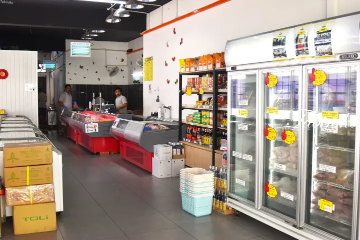 赤い陳列台や缶詰の棚、肉製品が並ぶガラス扉の冷凍庫がある精肉店の店内。