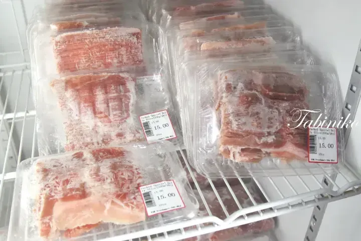 Frozen pork belly slices in plastic packaging on a supermarket shelf with price tags showing 15.00 MYR