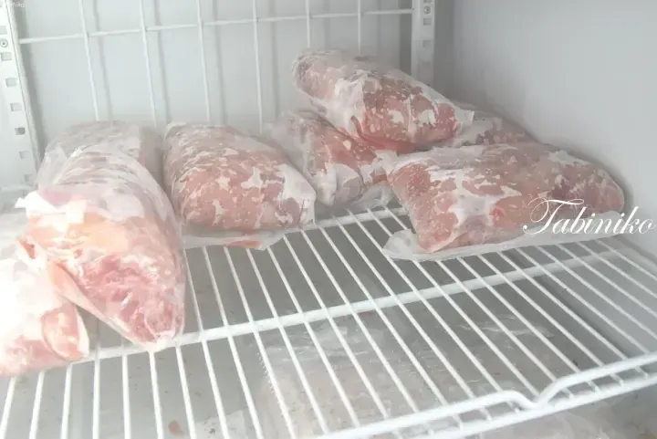 Frozen raw meat packages stored on a wire rack inside a freezer.
