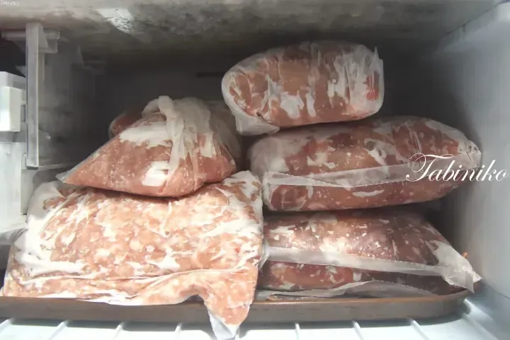 Stacks of frozen meat packages stored in a freezer compartment.