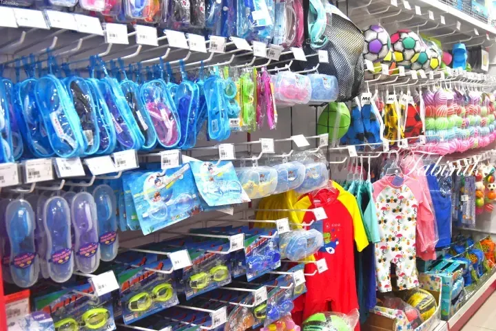 Shelves stocked with colorful swim goggles, snorkel sets, and children&rsquo;s swimsuits in a Malaysia retail store.