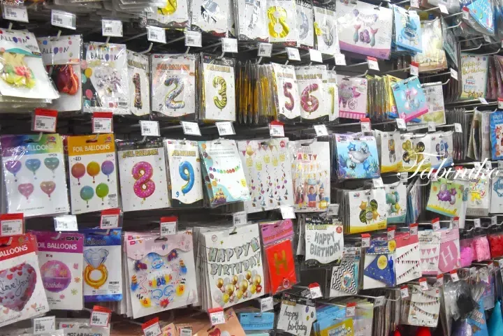 A display of colorful foil balloons and birthday party decorations hanging on store shelves.