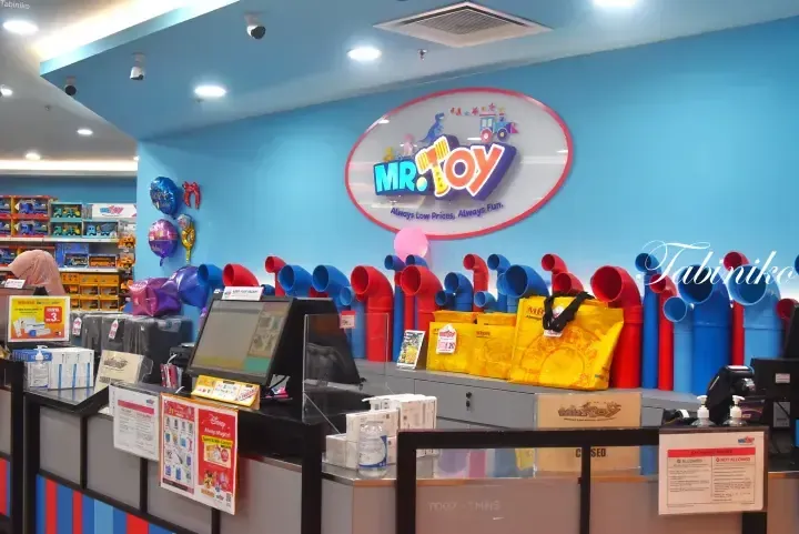 MR.DIY Toy store counter with colorful pipes display and yellow shopping bags at the checkout area.