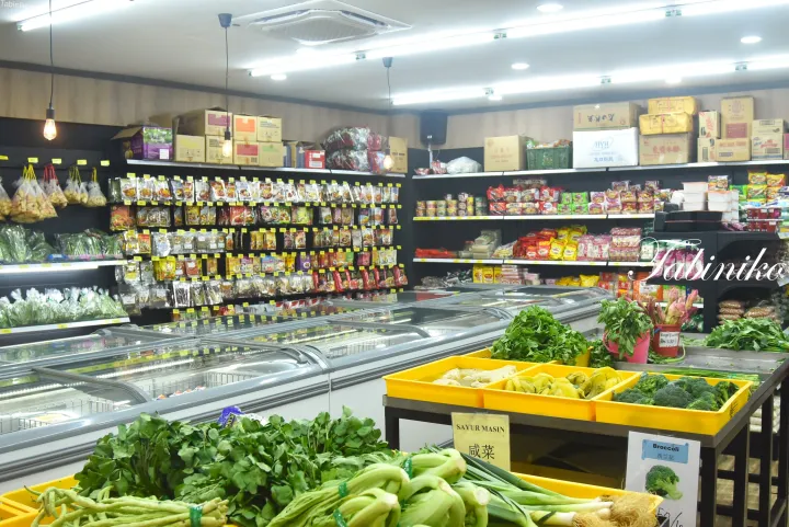 ブロッコリーや葉物野菜が黄色い箱に並ぶ鮮魚・野菜コーナーと、棚に並んだ包装食品が写るスーパーマーケットの店内。