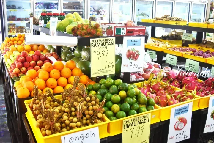 Colorful tropical fruits like rambutan, dragon fruit, and longan displayed in yellow crates at The Fruit House in Malaysia.