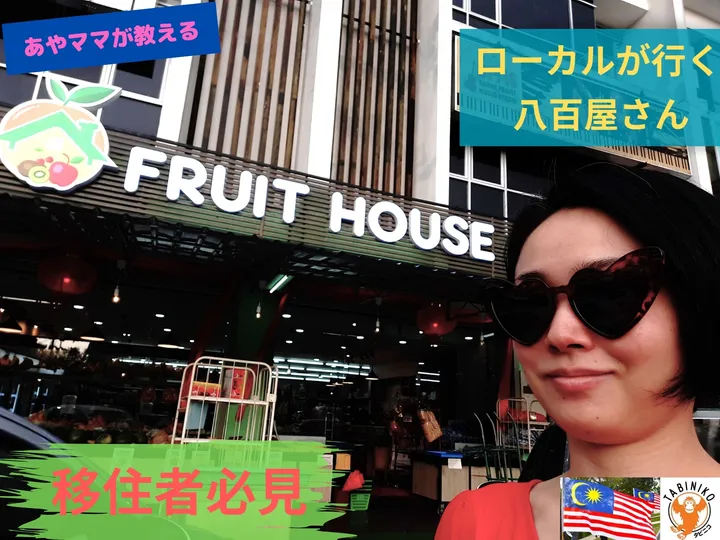 サングラスをかけた女性が「FRUIT HOUSE」の入り口の前に立っている。