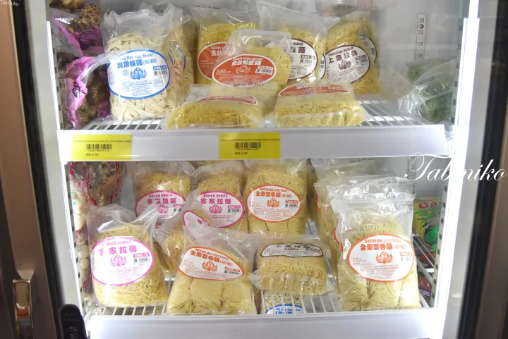 客家ラーメンやワンタン麺など、様々なパッケージされた生麺が陳列された冷蔵ショーケース。