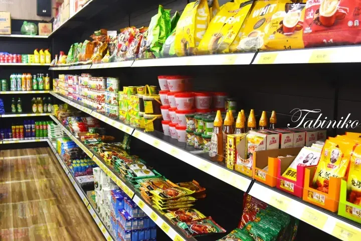 Well-stocked shelves in a Malaysian grocery store featuring brands like Aik Cheong, Yeo’s, and Wang Wang.