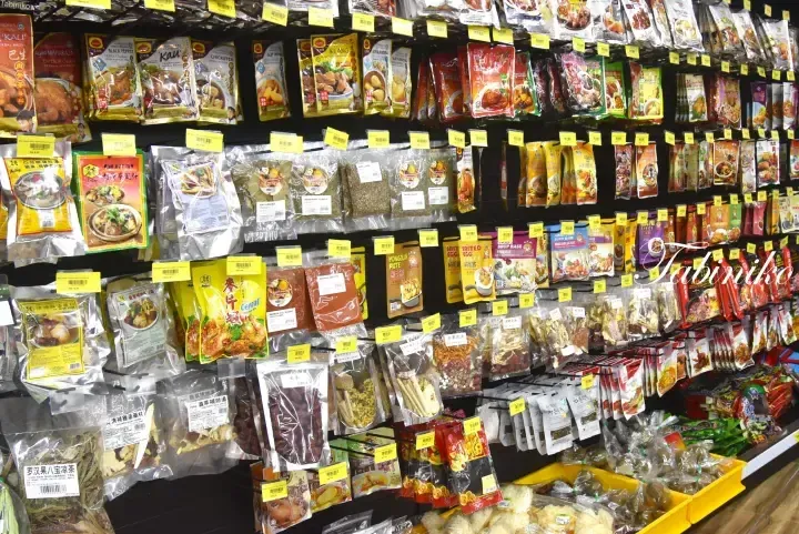 Shelves stocked with various packaged Malaysian food products, spices, and herbal ingredients in a grocery store.
