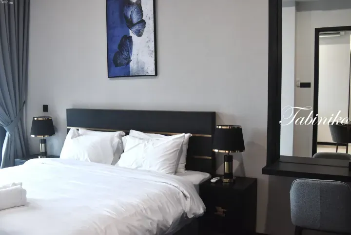 Modern hotel bedroom with a king-size bed, blue butterfly artwork, and a vanity desk.