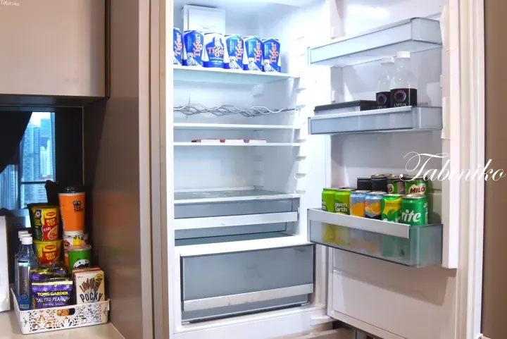 Open refrigerator stocked with Tiger beer and beverages, next to a basket of snacks including Tong Garden peanuts and Pocky.