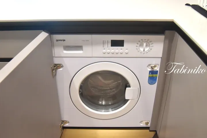 Built-in Gorenje washing machine with 7+4kg capacity and 1200rpm spin speed installed in a modern kitchen cabinet.
