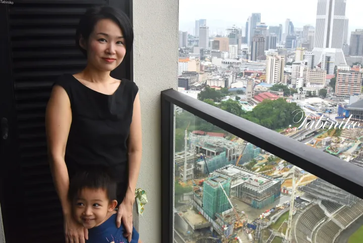 都会のスカイラインと建設現場を見下ろすバルコニーに立つ女性と幼い男の子。