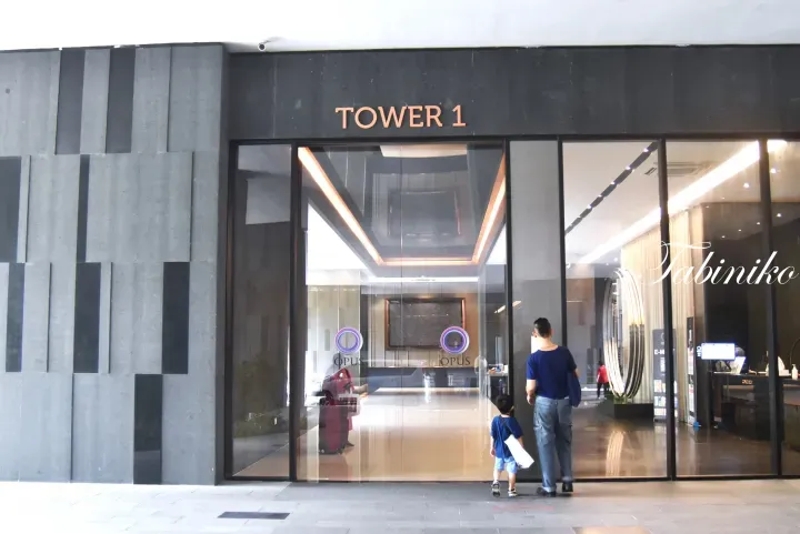 Tower 1 entrance at Opus Residences with glass doors and a father and child walking inside.